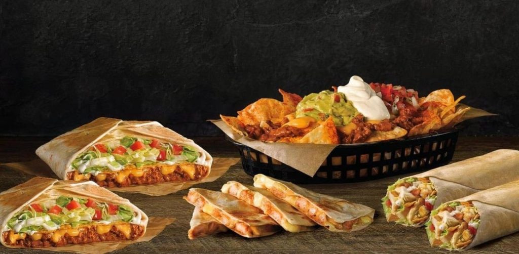 Taco bell menu items are placed on a table including tacos, nachos and more